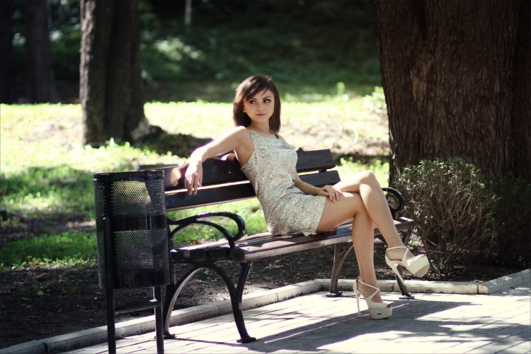 Девушка сидит на скамейке нога на ногу