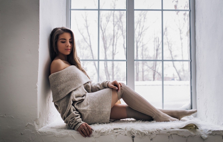 Девушка в свитере у окна